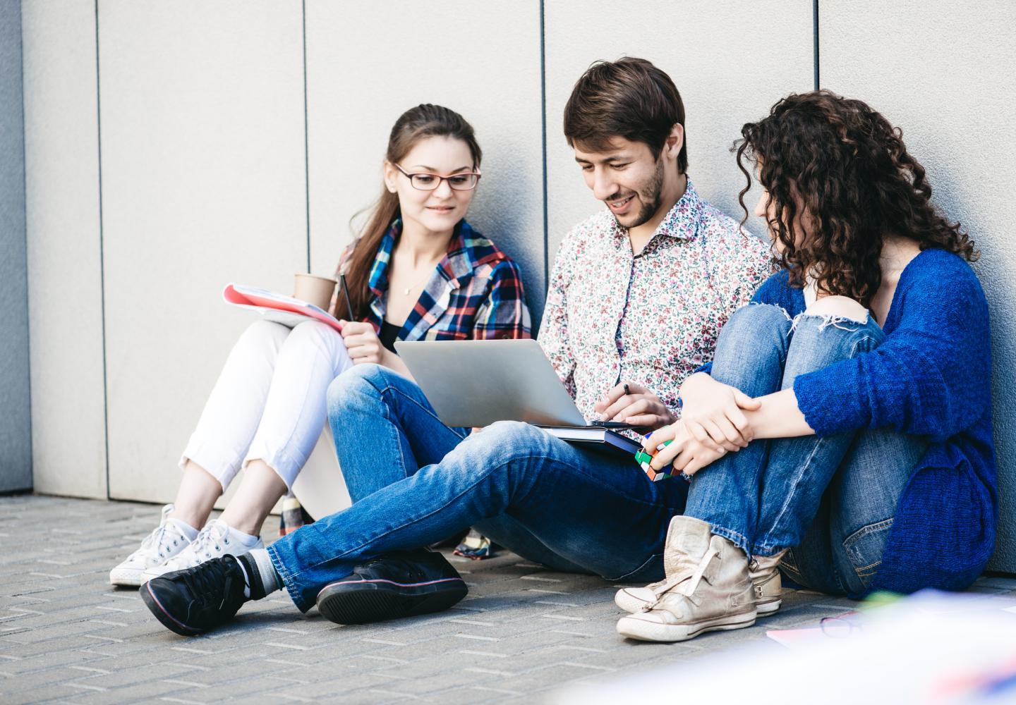 Young people are using different gadgets and smiling, sittin